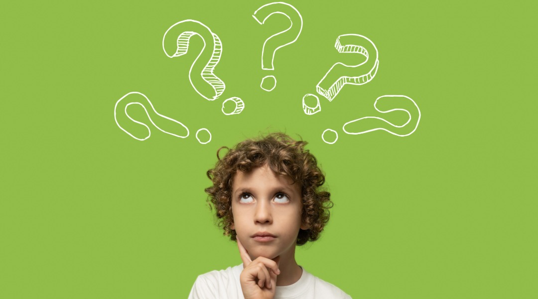 A picture of the head of a 10 year old boy with a questioning look on his face and 5 question marks drawn above his head. He wants to know, which is better Montessori vs traditional school.