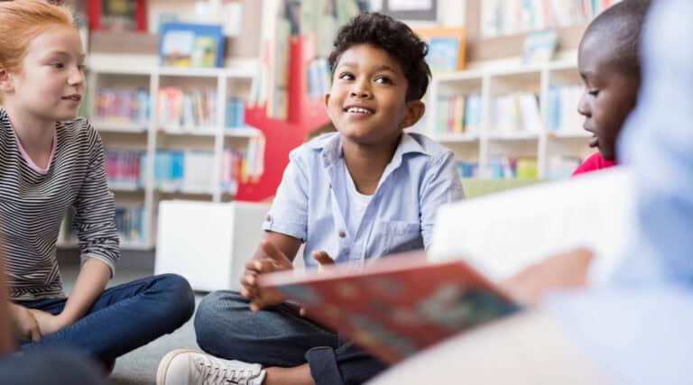 A young boy in a small group of students working on vocabulary development activities.