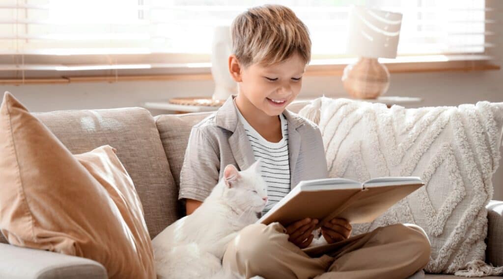 A boy and his white cat enjoying a cat book for kids.