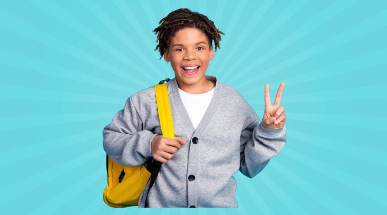 An upper elementary student wearing a yellow backpack smiling and giving the peace sign with his fingers.