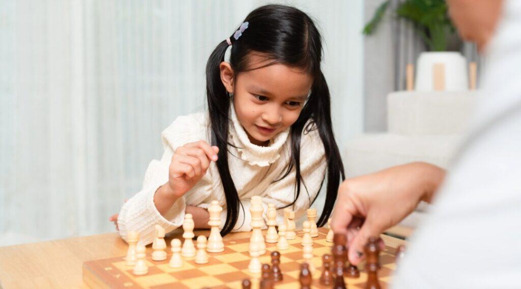 A 10 year old girl is playing chess against her classmate and learning through playing.
