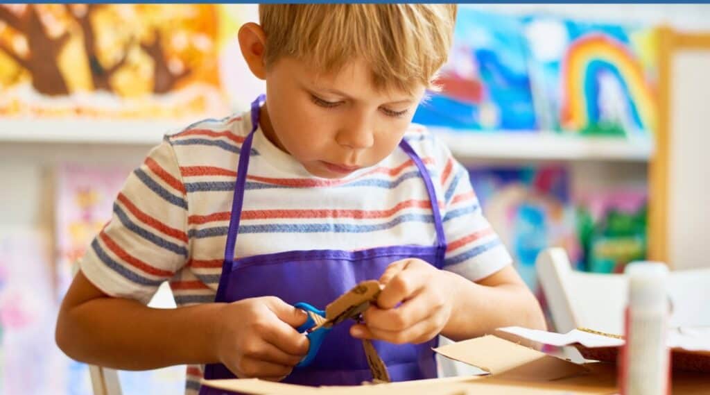 A young boy cutting out his net of a cube printable so he can play some dice games.