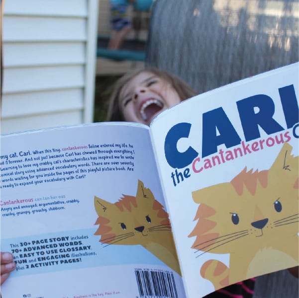 A picture of a young girl with her head tilted back in laughter as she reads Carl the Cantankerous Cat, a great picture book for 5th graders.