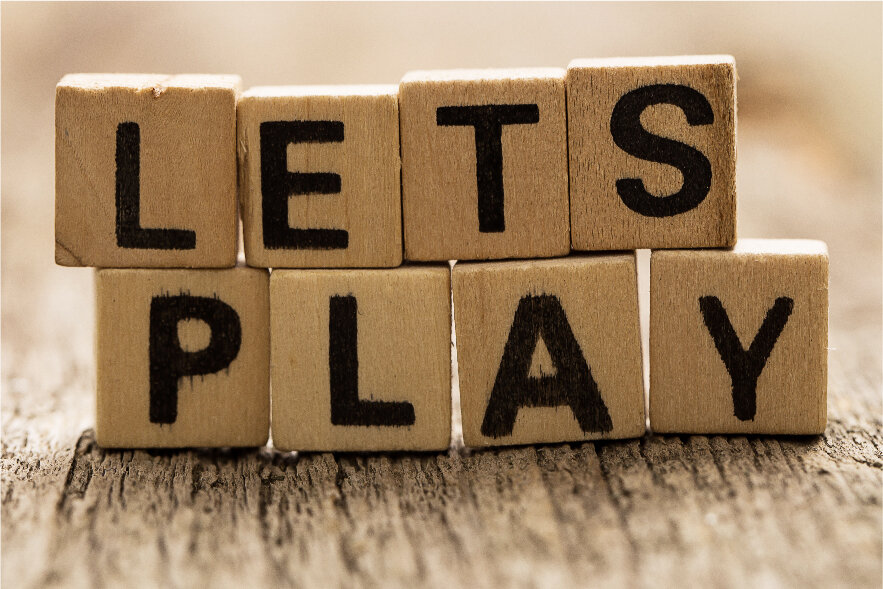 The words "Lets Play" are spelled out using Scrabble letter tiles. Scrabble is one of many awesome summer reading activities elementary kids love!