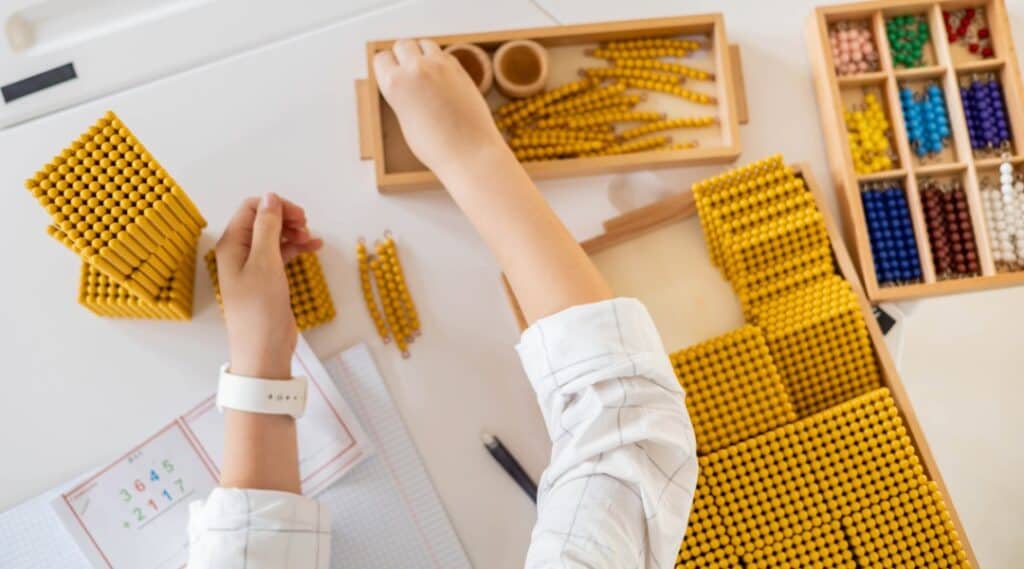 An elementary student using Montessori command cards with the golden bead material.