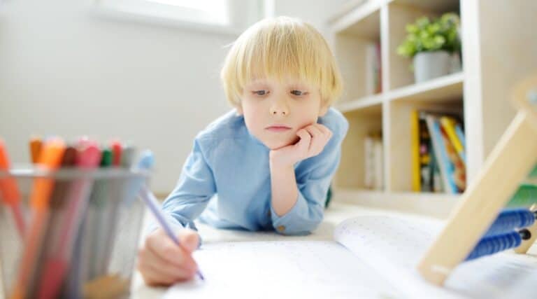 A young elementary student doing a math question on the floor using Montessori command cards.