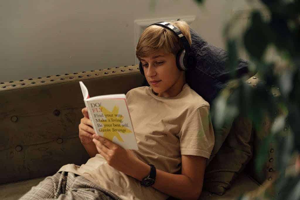 A Boy listening to an audiobook and following along in a book.