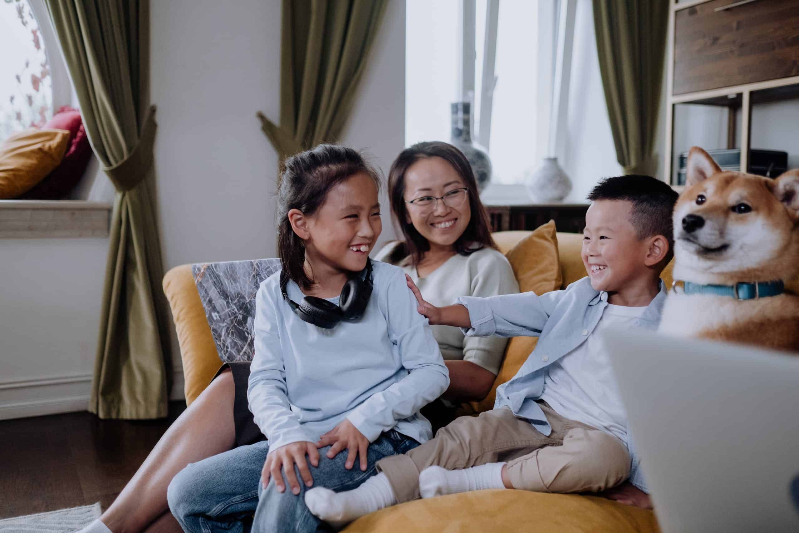 A Happy Family Sitting on the Couch while Playing with their Dog