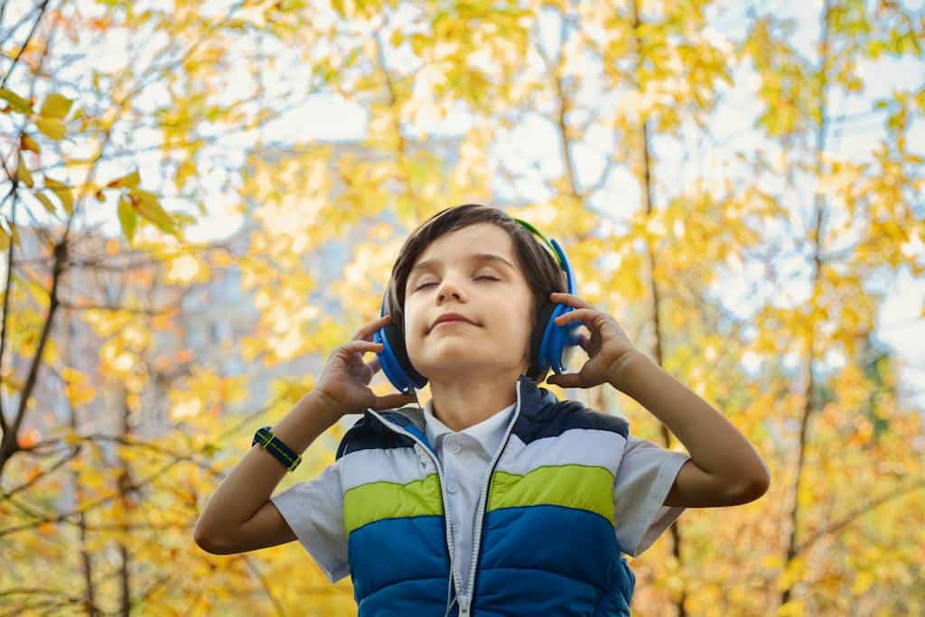 Photo of a Boy Listening  to an audiobook through Headphones