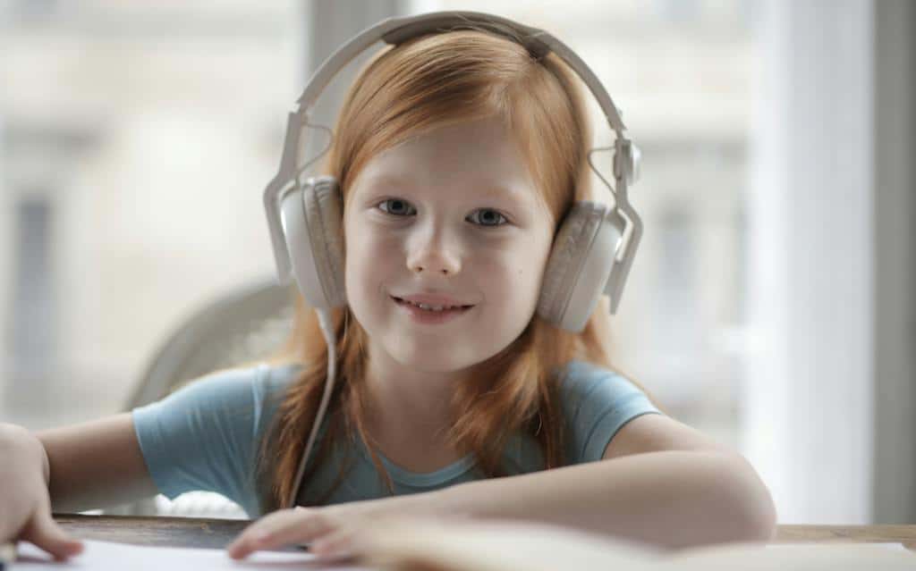 Photo Of Girl Using Headphones to listen to an audiobook in the classroom.
