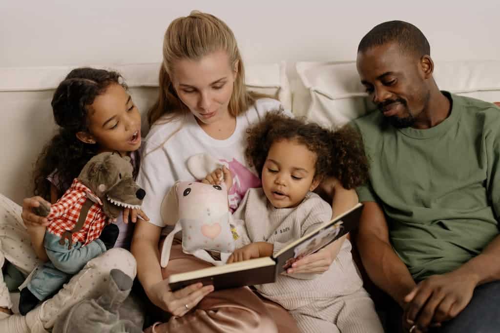 A picture of a family of four sitting on a couch enjoying their family book club read aloud together.