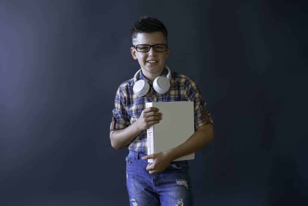 Smiling Boy in Glasses with Book in Studio