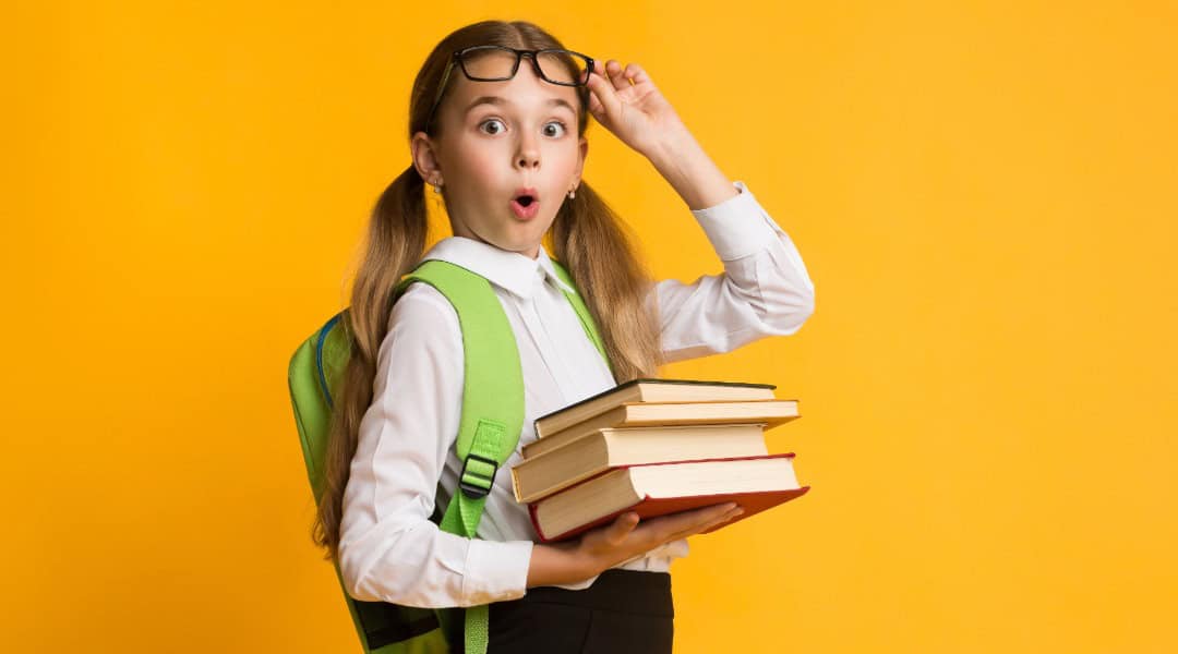 A female elementary student wearing a backpack, holding books and looking excited about her book report options.
