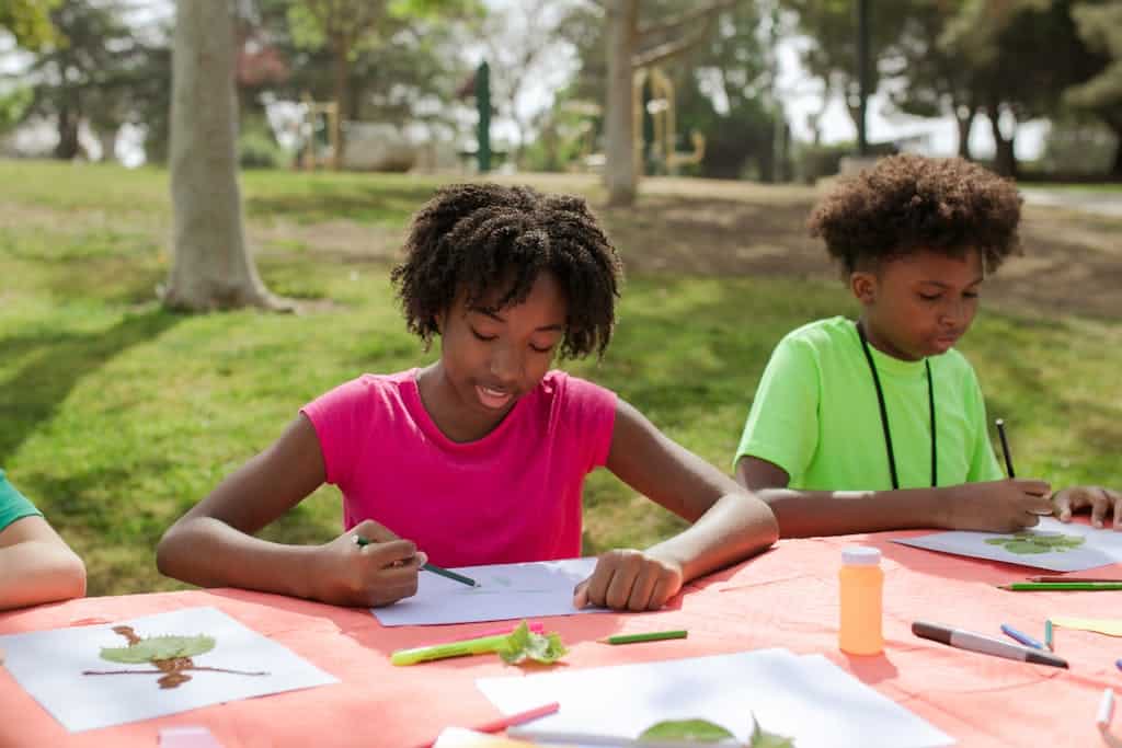 A Young Girl and Boy Writing and Drawing their very own comic book outside at a Table