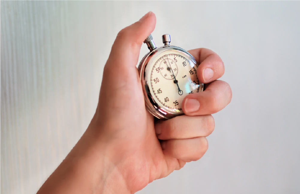 An image of a hand holding a stopwatch. Using a stopwatch is a great way to challenge kids in a library scavenger hunt.