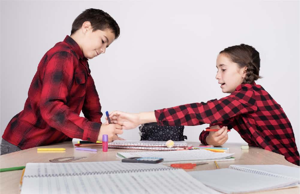 A boy and girl, both wearing read and black plaid button up shirts, working together to complete a team library scavenger hunt.
