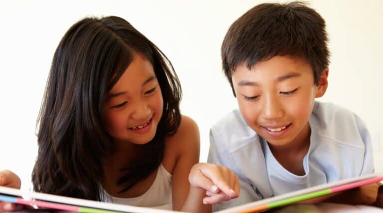 Two asian kids looking at a picture book