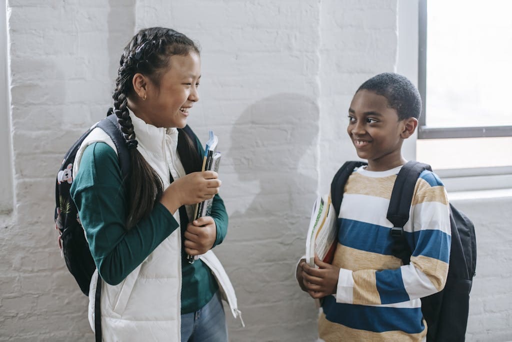 Happy diverse schoolchildren communicating in corridor during break about the educational quotes they learned.