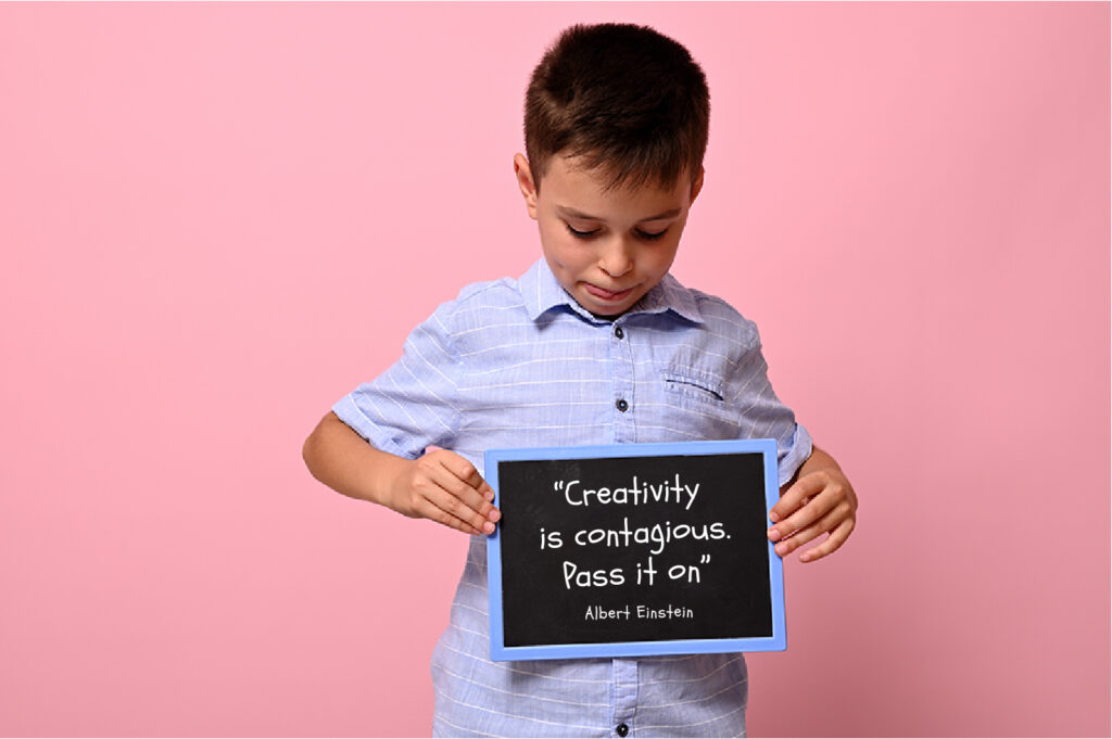 A young boy holding a small sign that has a short quote on it.