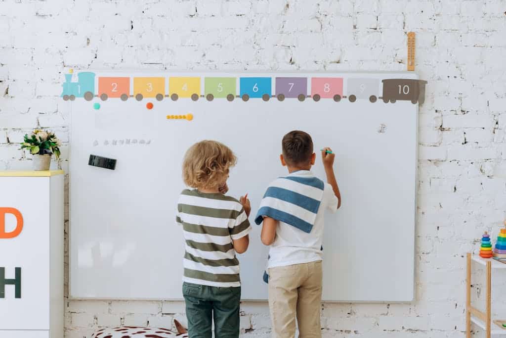 2 Boys Writing different parts of speech on the classroom Whiteboard