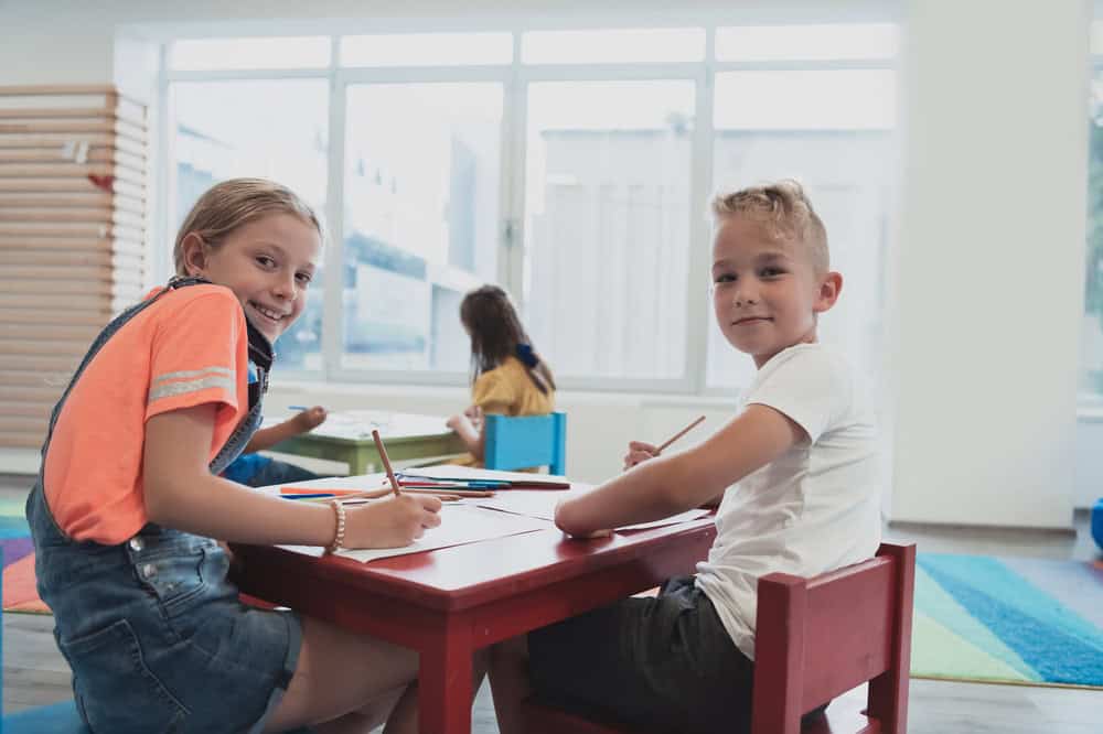 Girl and boy sitting at a table together as the class plays parts of speech bingo. 