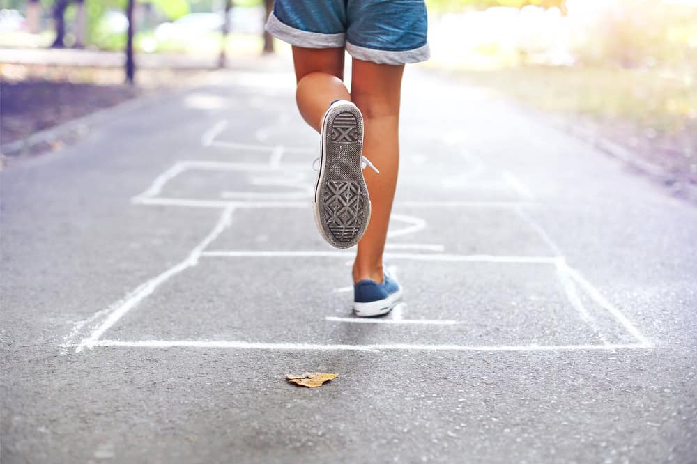 Kid playing hopscotch. This makes for one of the most engaging games to help teach parts of speech.