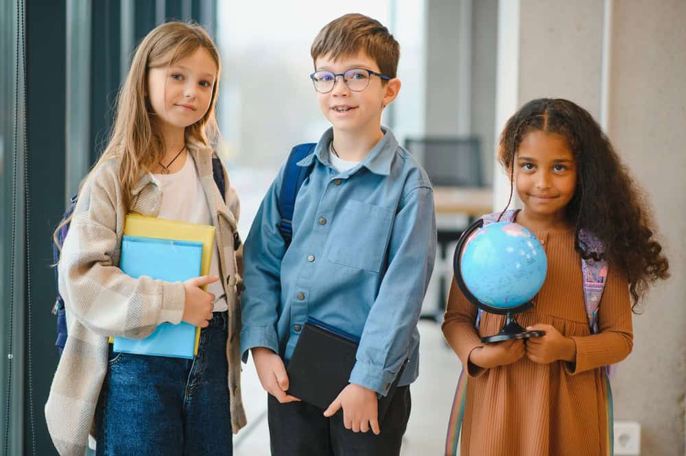 Three Montessori elementary students in the hallway of school walking to their classroom.