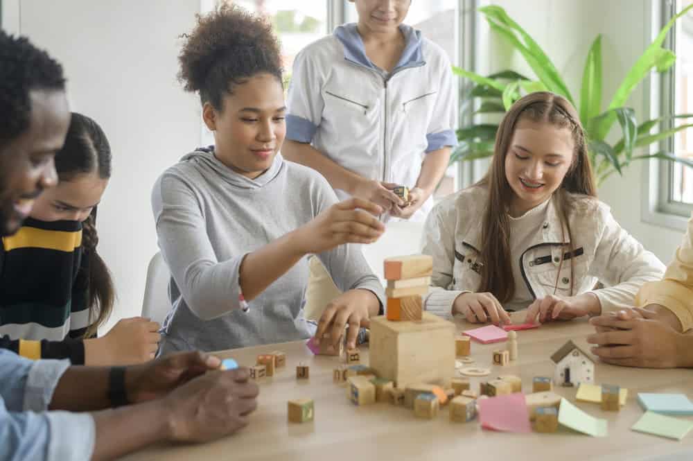 A group of upper elementary Montessori students engaging in hands-on learning with building blocks.
