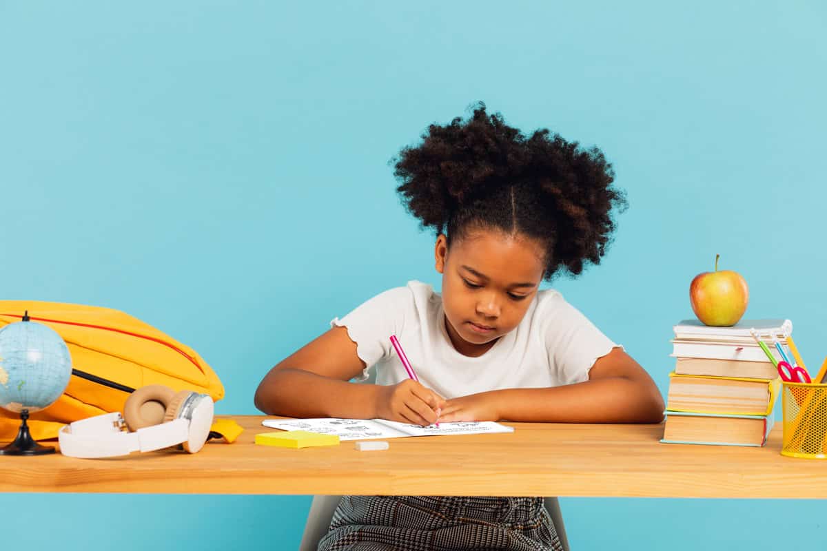 An image of a young girl sitting at a table coloring The Best Ever Cat Facts For Kids book.