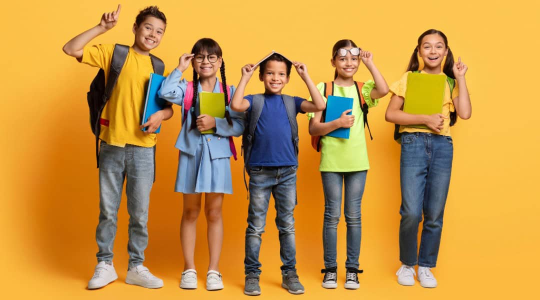 Five upper elementary Montessori students posing for the camera, all smiles.