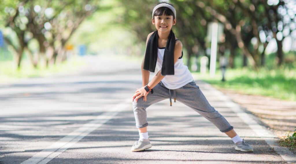 Cute young female child stretching with running clothes on reading for a fitness scavenger hunt