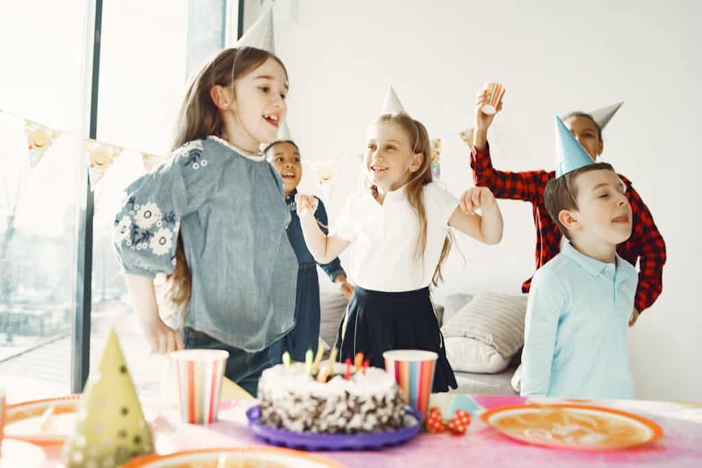 Kids enjoying a birthday party with cake, an alphabet scavenger hunt, and decorations indoors
