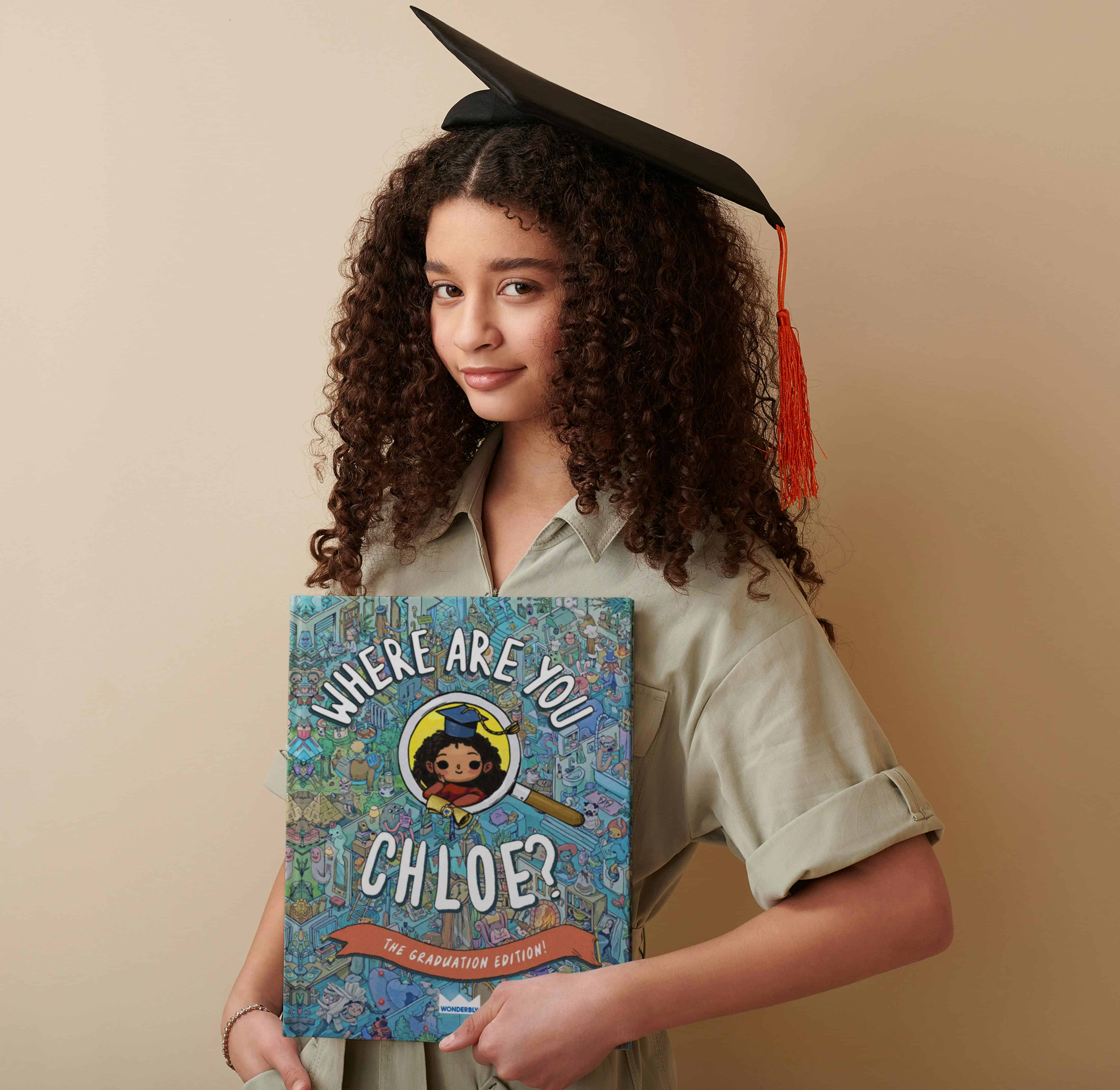 An elementary graduate wearing a grad cap holding a personalized book, such a fun graduation gift for elementary.