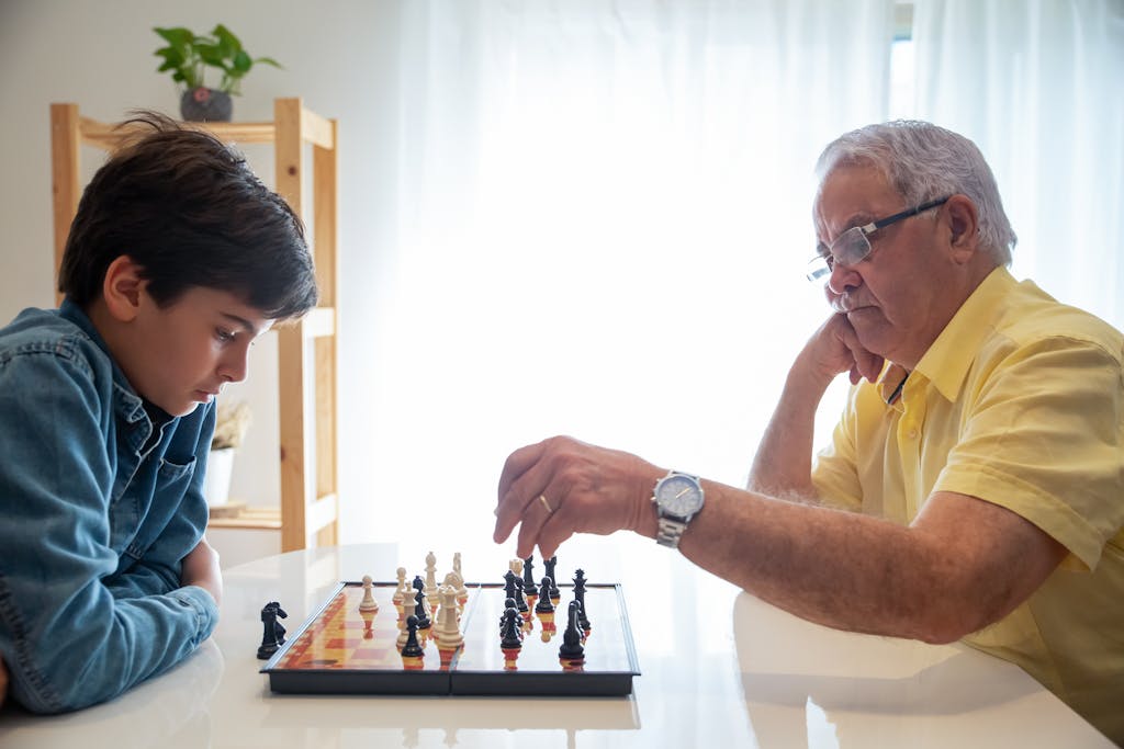 A thoughtful chess game between a grandfather and grandson indoors, promoting family bonding and strategy skills.