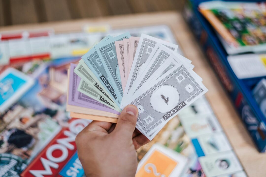 Close-up of Monopoly money held during a board game session, with blurred background. Board games
