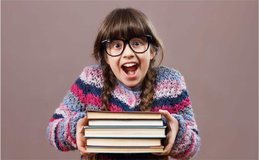 An image of a 12 year old girl holding a stack of books. She received a bookstore gift card as a thoughtful elementary school graduation gift.