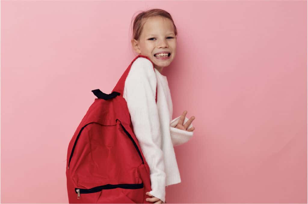 An image of a 12 year old girl holding a red backpack.
