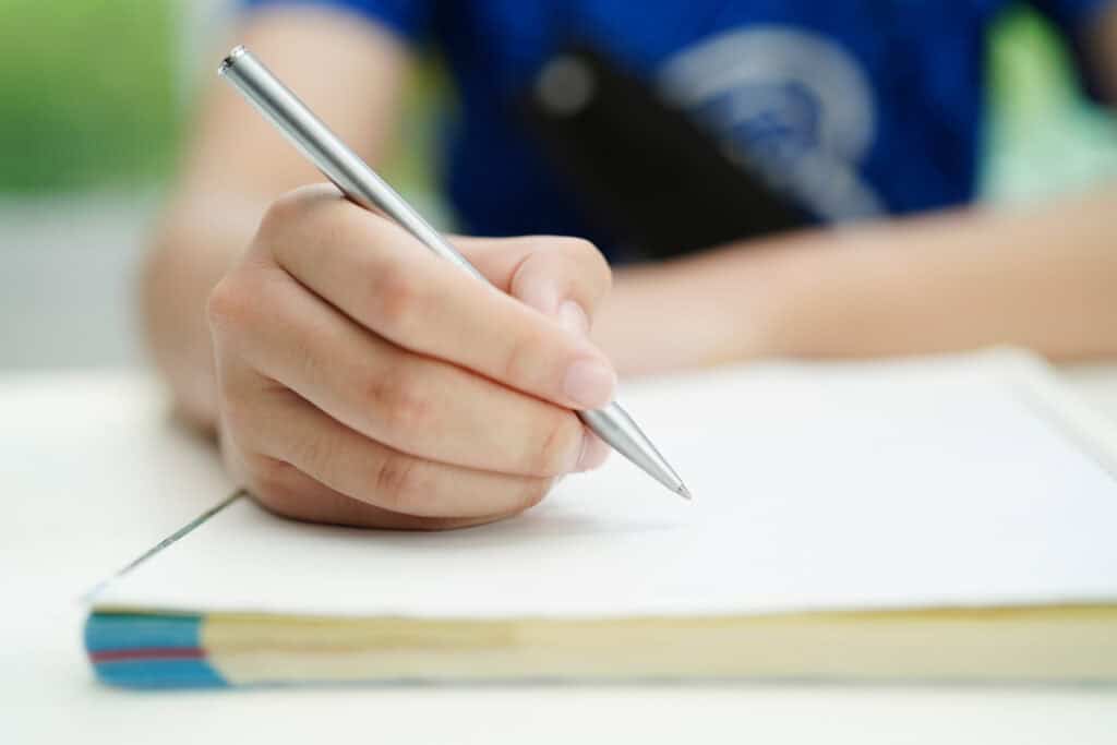 Middle school student writing homework with a nice engraved pen they got as an elementary graduation gift.