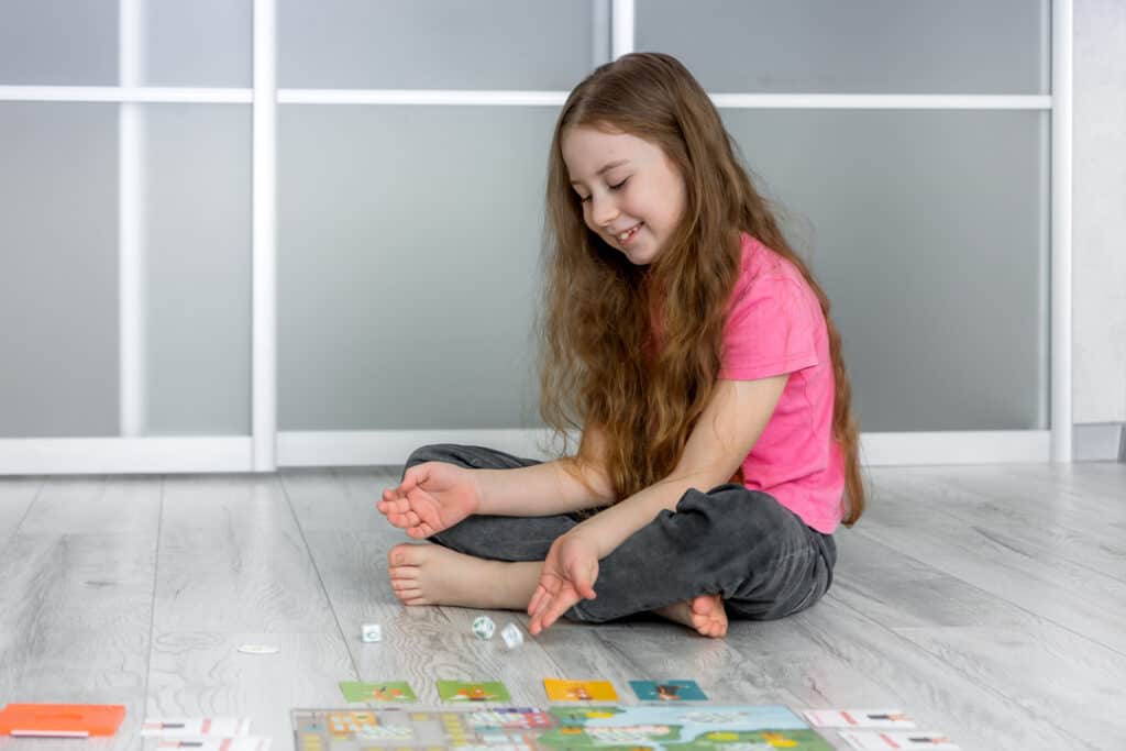A young girl excitedly plays a board game, a great elementary graduation gift!