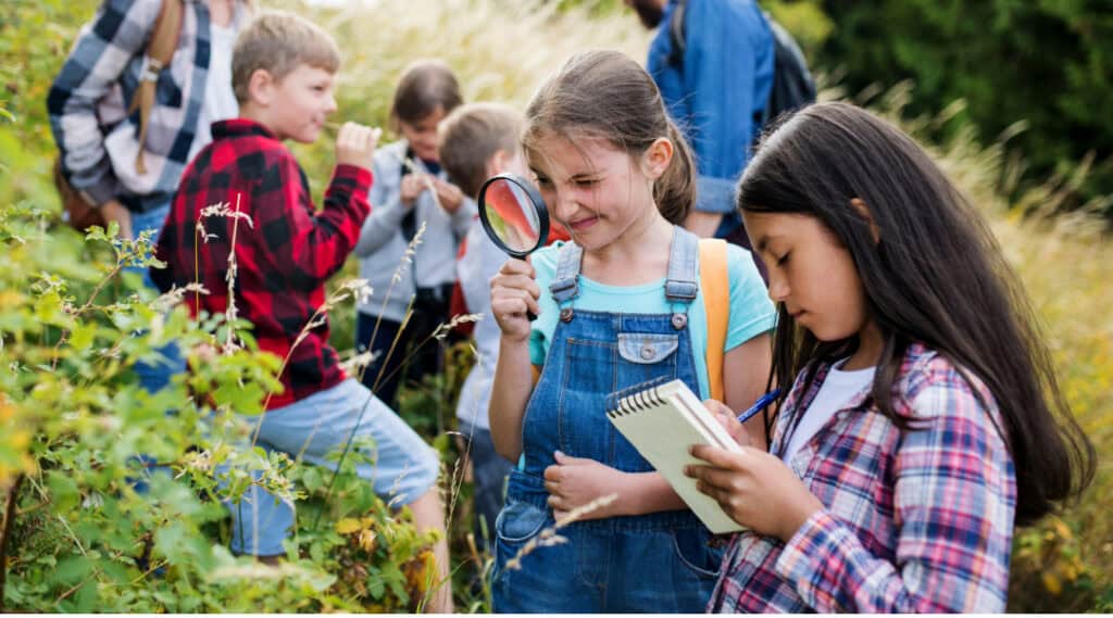 An elementary class on an outdoor field trip where they are using an alphabet scavenger hunt printable.