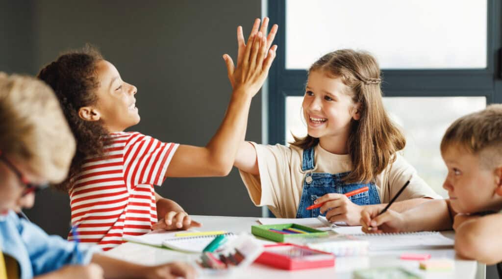 Two 9-year old female students giving each other a high five after completing group work.
