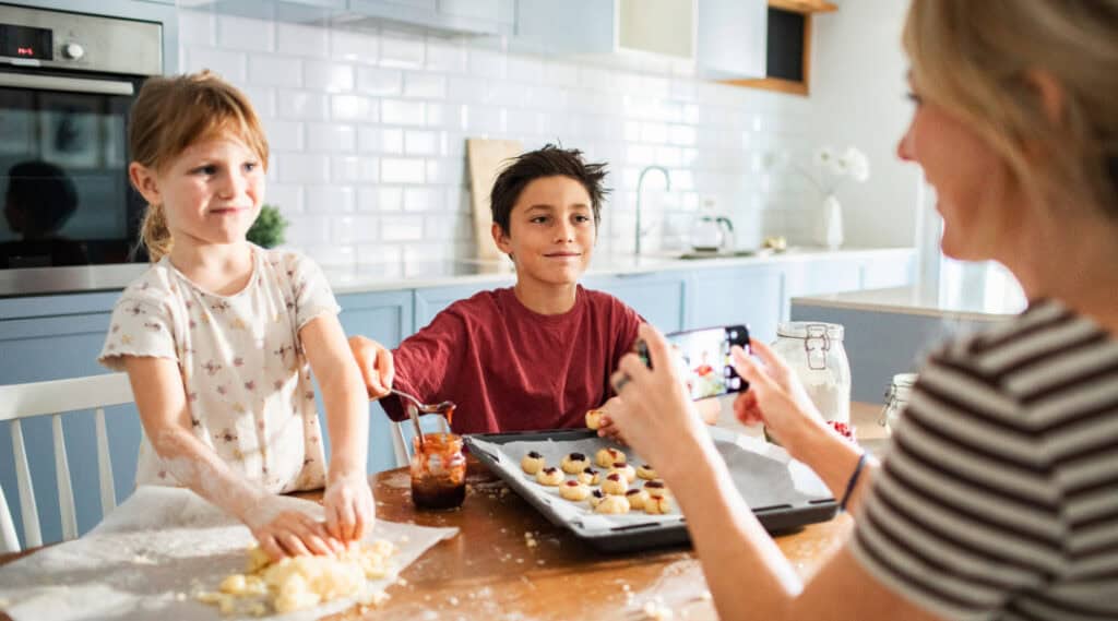 A boy and a girl in the kitchen with their mom baking cookies.
