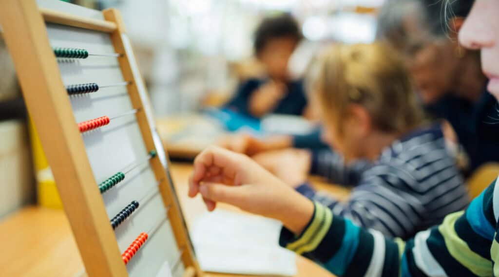 A young student sitting at a table practicing math in a Montessori elementary classroom.