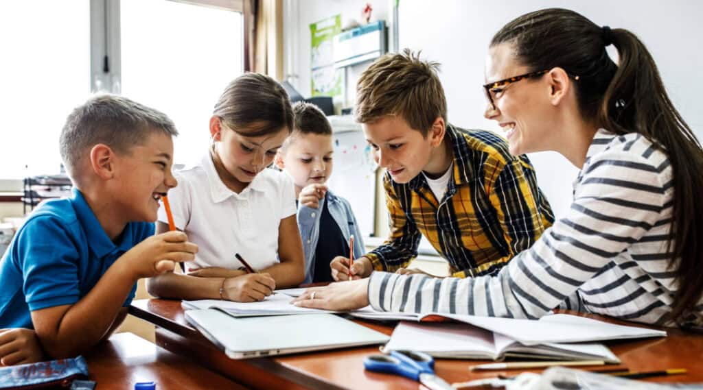 A teacher working with 4 students at a table in a Montessori elementary classroom.
