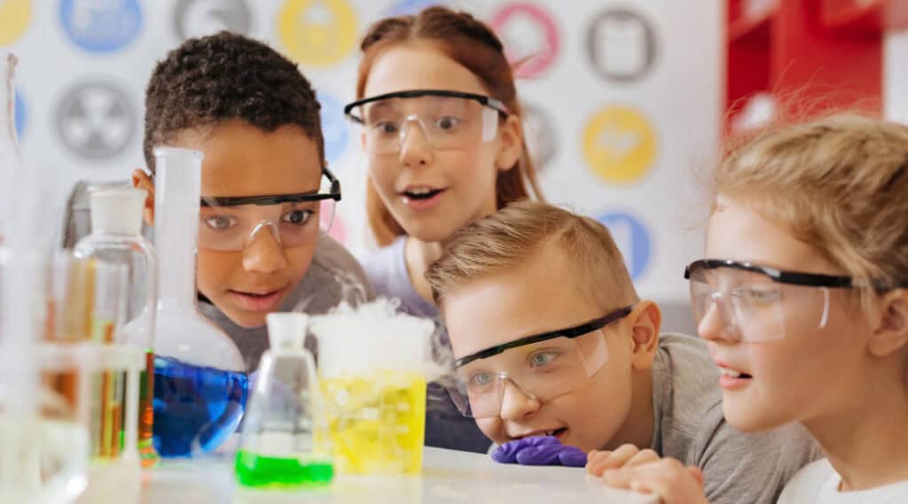 Four elementary aged children working together  on a science experiment in a Montessori elementary classroom.