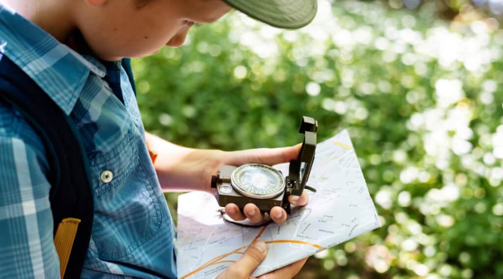 Summer math activities that include measuring are great - here a boy holds a compass.