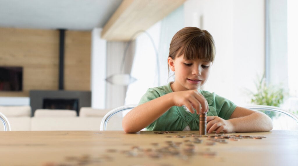 A young girl stacking coins.