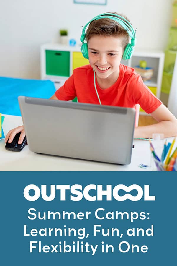 A young boy smiling at his computer. He is engaged in one of his virtual summer camps.