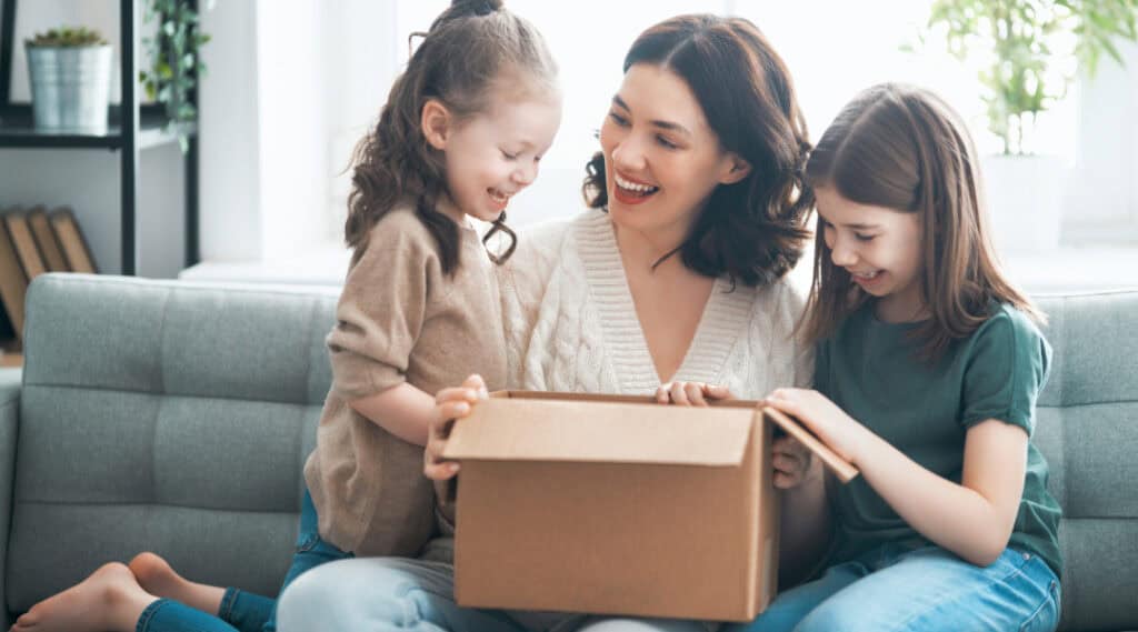A mom and her two daughters are unboxing their KiwiCo monthly subscription box.