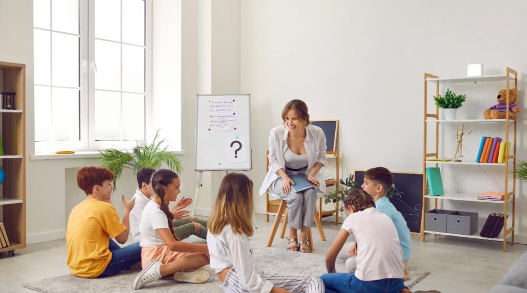 A picture of a teacher with a small group of students in a Montessori elementary classroom working on the carpet.